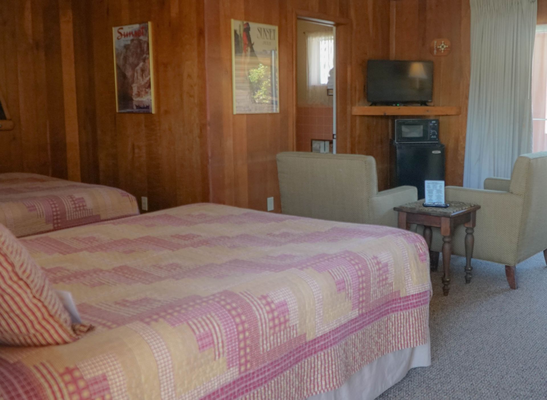 A hotel room with two beds , a chair and a television.