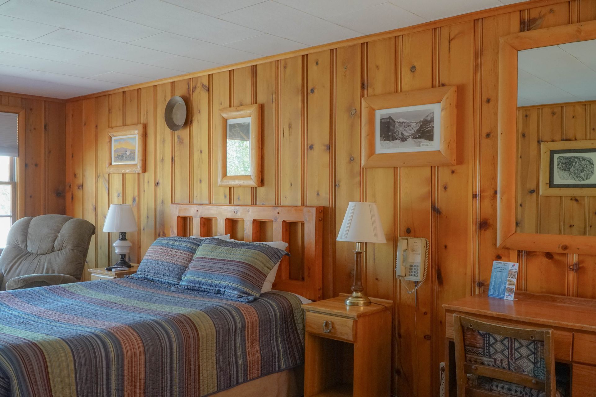 A bedroom with a bed , nightstand , chair and mirror.