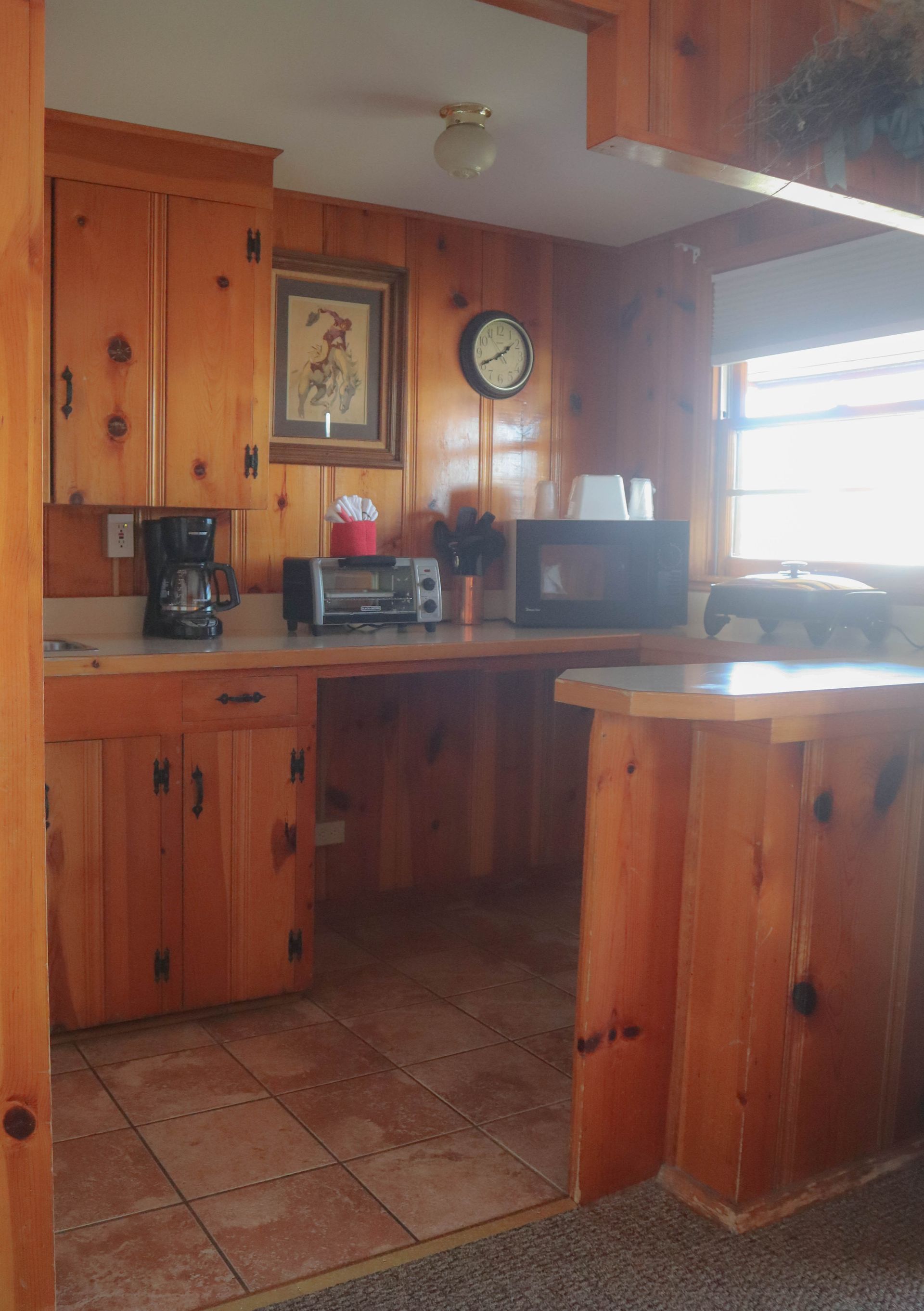 A kitchen with wooden cabinets and a clock on the wall