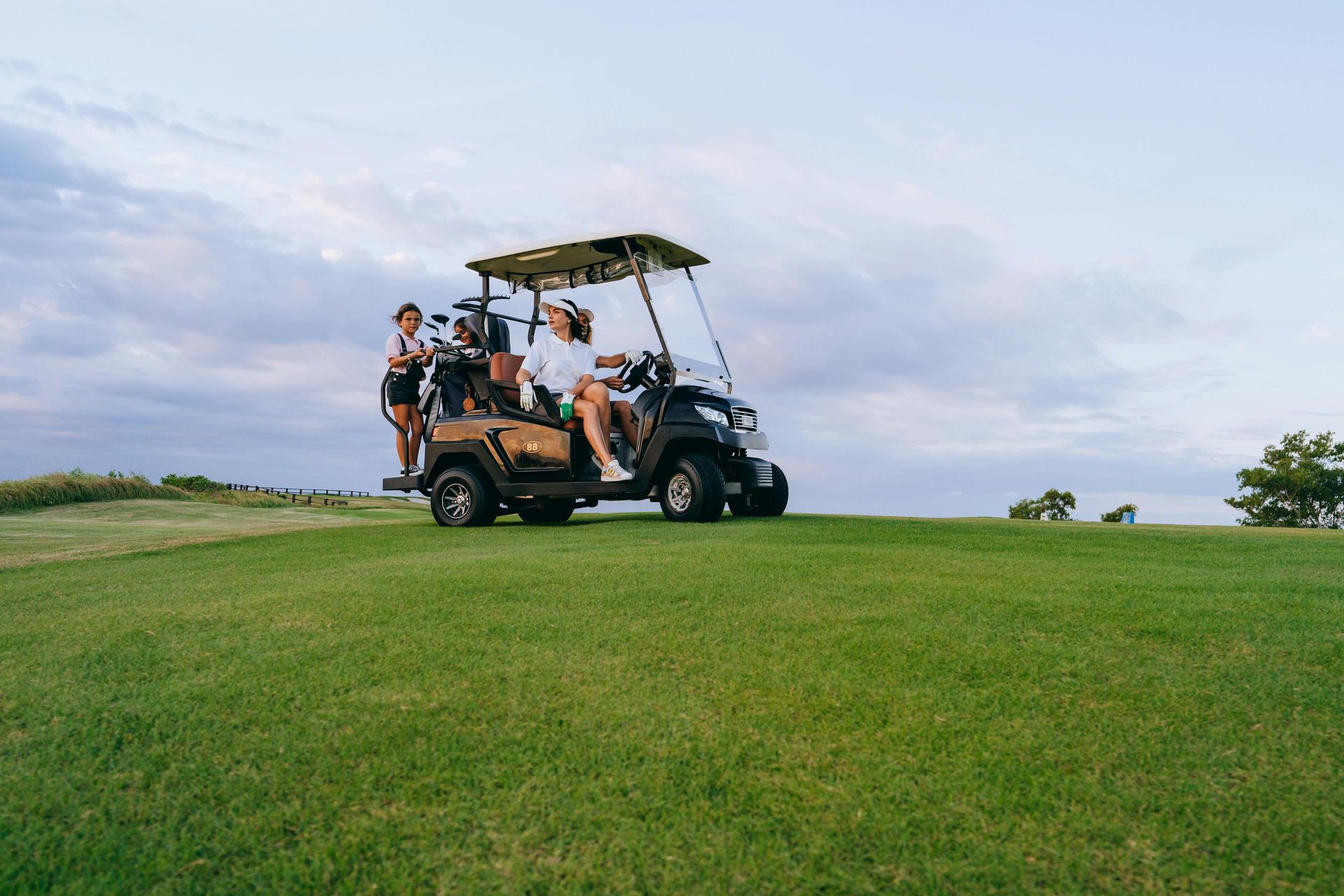 A group of people are riding in a golf cart on a golf course.