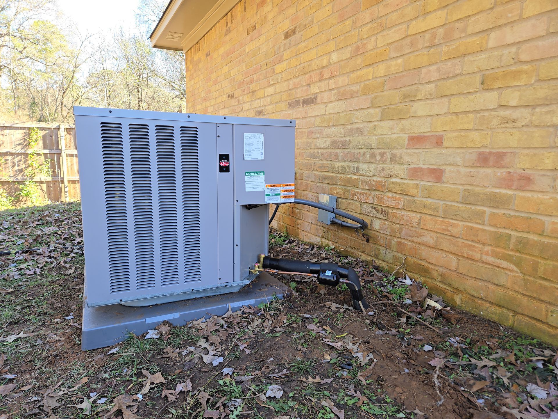 An air conditioner is sitting on the side of a brick building.