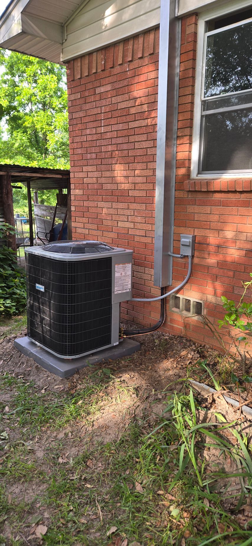 An air conditioner is sitting outside of a house.