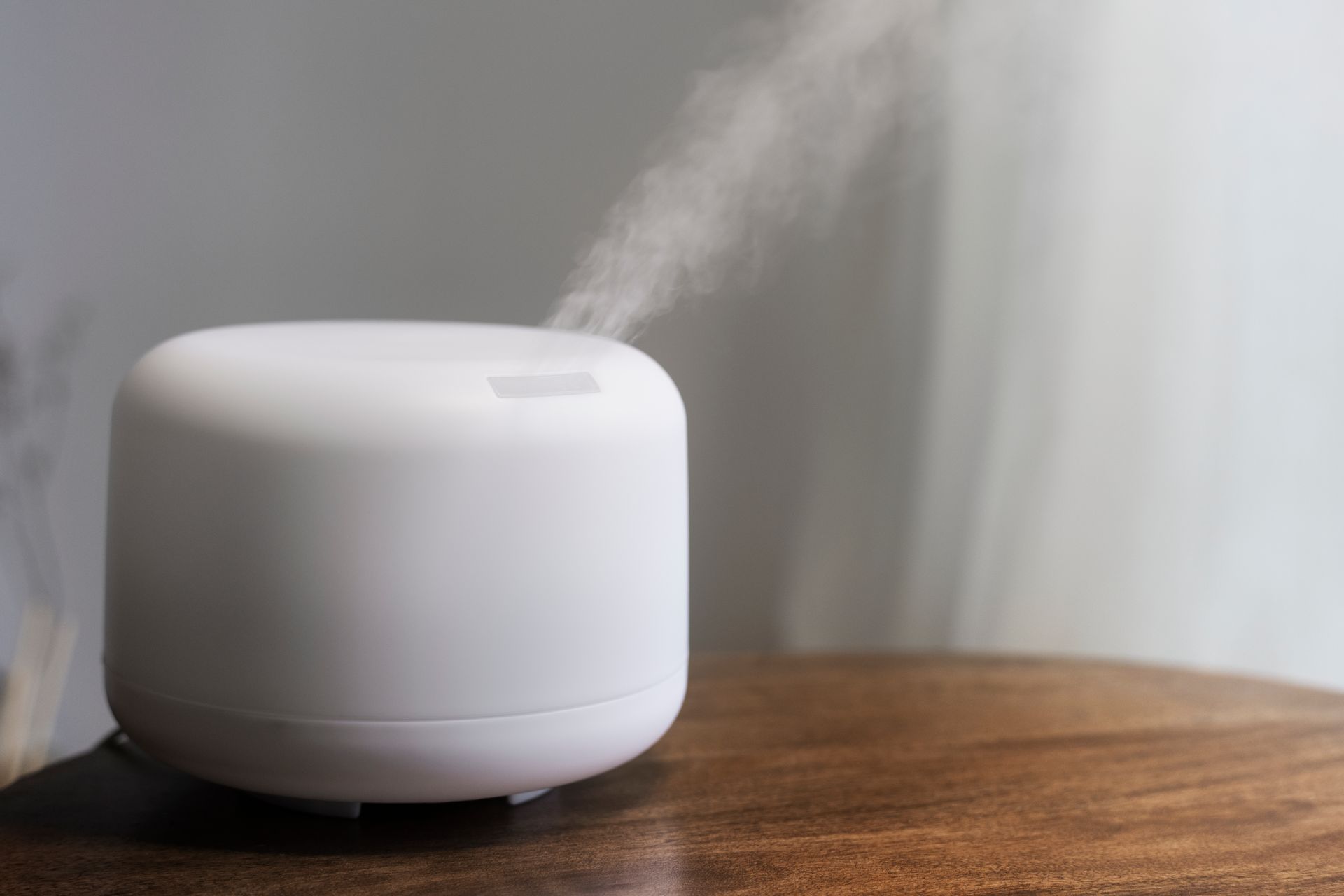A white ultrasonic humidifier is sitting on a wooden table.