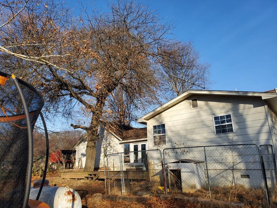 House with a tree, trampoline, and fence on a sunny day.