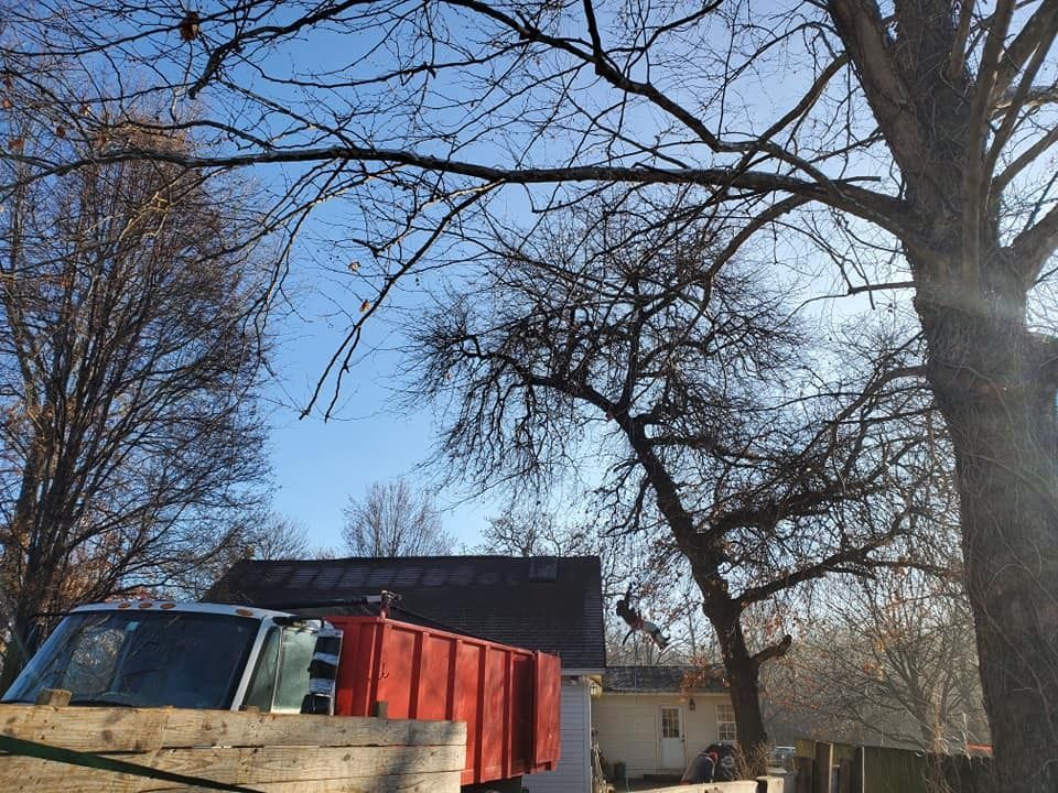 Red truck in front of a house, bare trees against a blue sky.