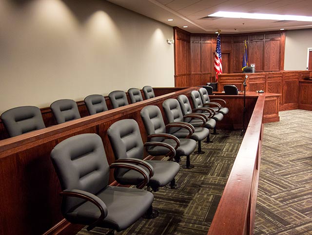 A row of chairs in a courtroom with a flag in the background