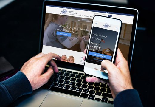 Person using a laptop and smartphone to browse a website.