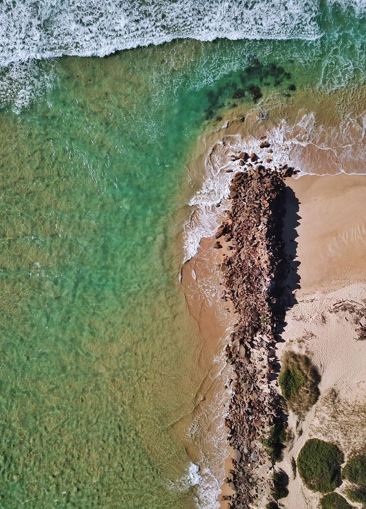 An Aerial View of a Beach With Waves Crashing on the Shore — Able Building And Pest Inspections In Urunga, NSW