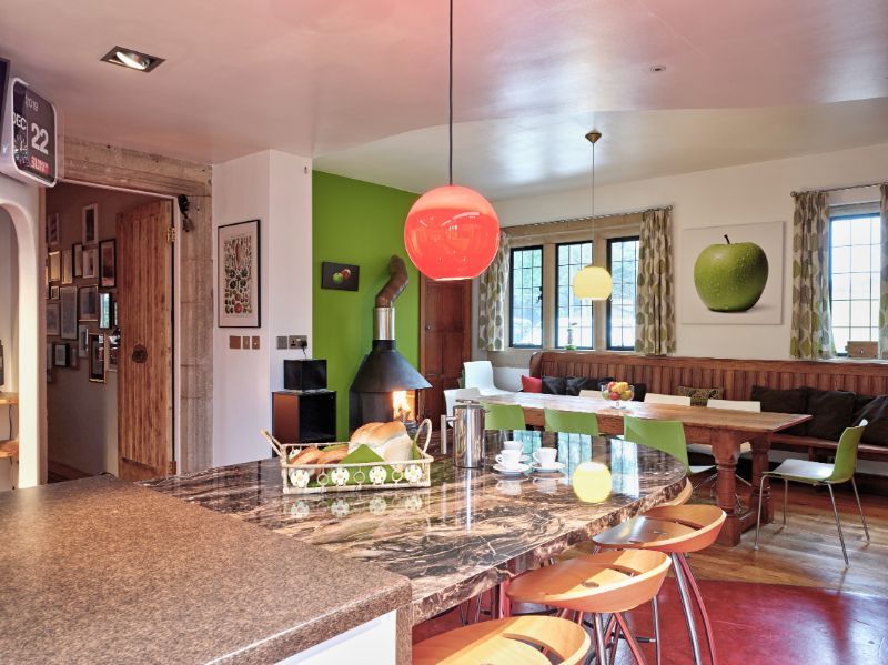 Modern dining room with colorful pendant lights, glass table, and brick fireplace