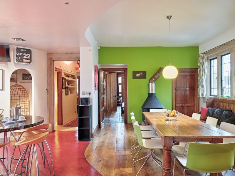 Bright dining room with green accent wall, wooden table, fireplace, and hardwood floors