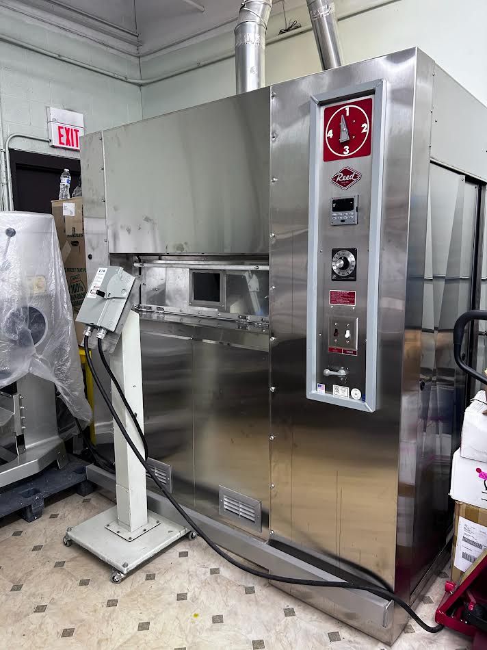 Large stainless steel industrial oven with control panel in a commercial setting.