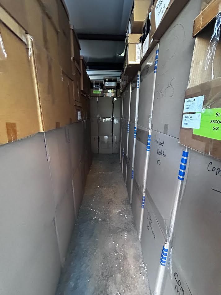 Narrow storage hallway lined with cardboard boxes on shelves.