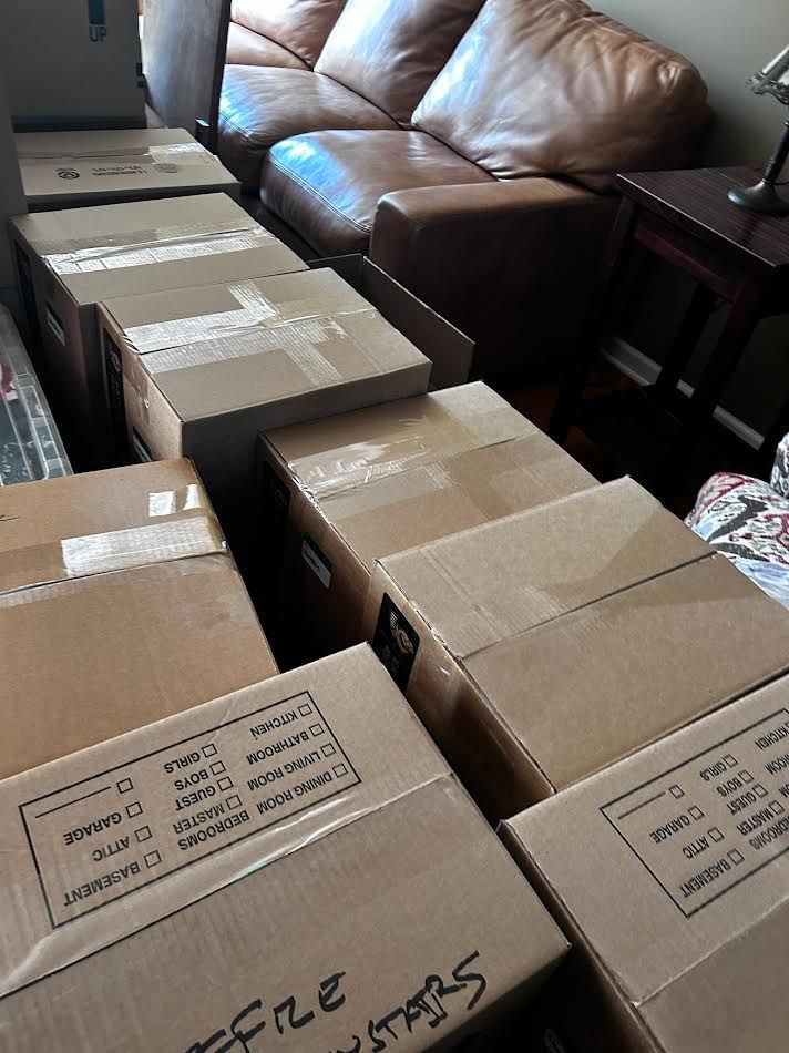 Cardboard boxes packed for moving, arranged in front of a brown leather couch.