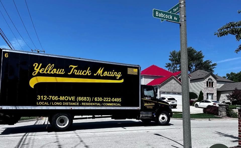 Black moving truck with yellow logo on a residential street.