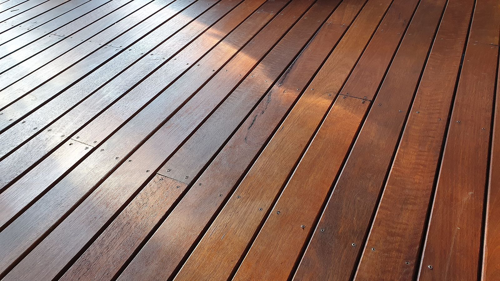 A close up of a wooden deck with the sun shining on it