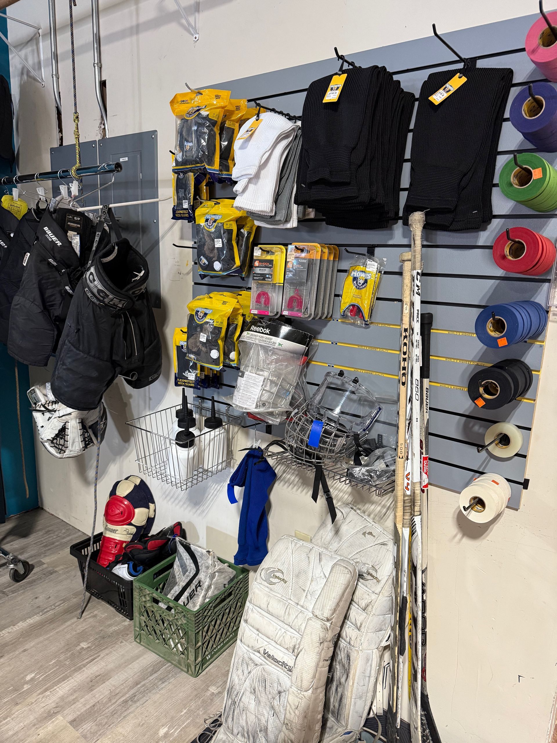 A room with a lot of hockey equipment hanging on the wall