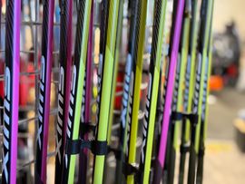 A bunch of skis are hanging on a rack in a store.