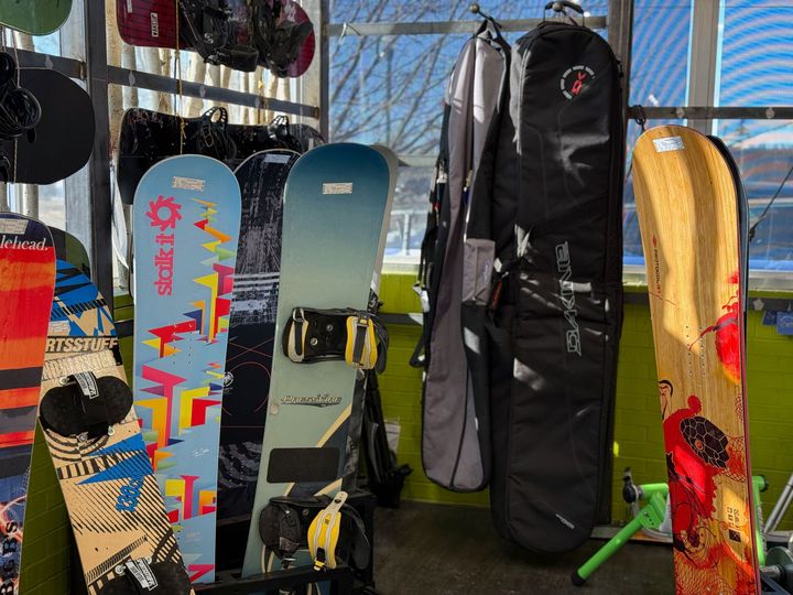 A bunch of snowboards are hanging on a rack in a store.