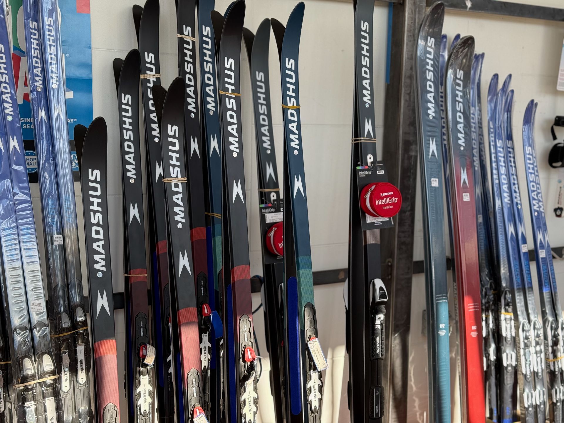 A row of madshus skis are lined up on a wall