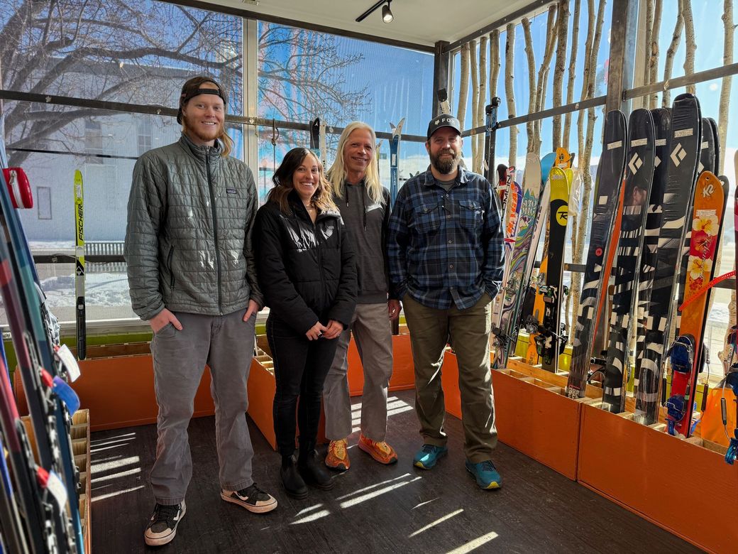 A group of people are standing in a room with skis on display.