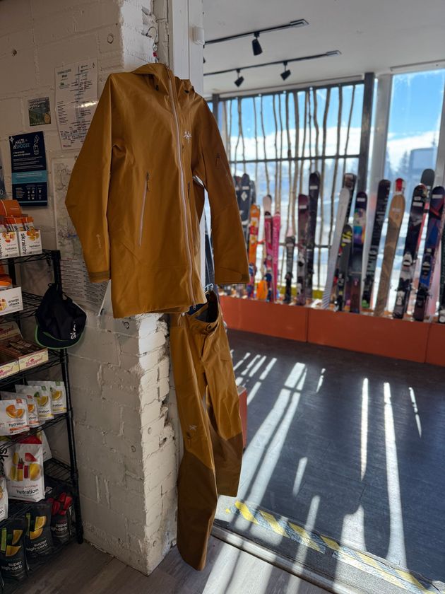 A brown jacket and pants are hanging on a pillar in a store.