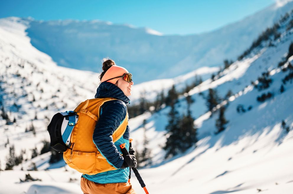 A person with a backpack is hiking up a snow covered mountain.