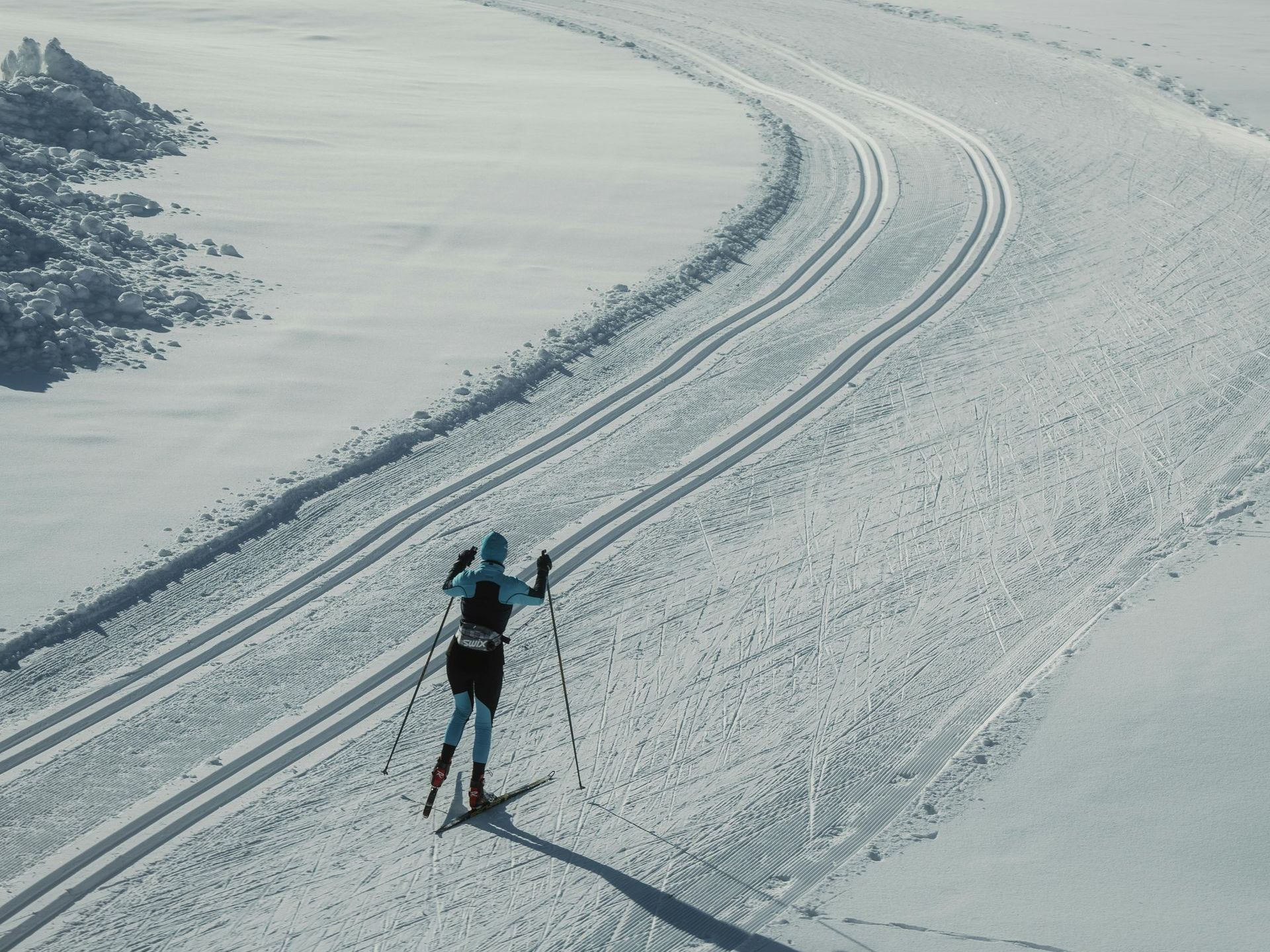 A person is skiing down a snow covered road.