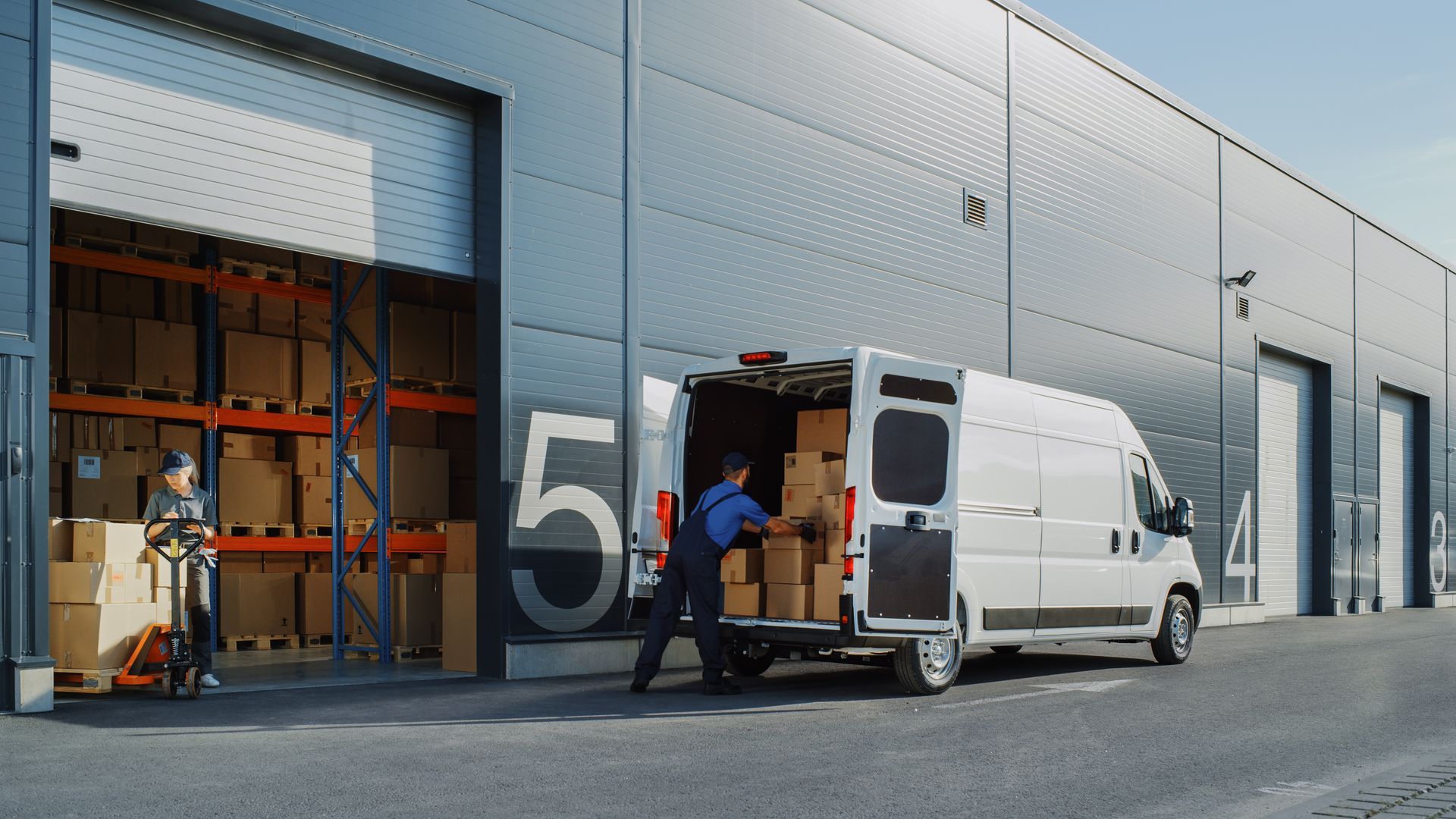 Workers are loading boxes into the delivery van at the warehouse. Workers are loading boxes into the delivery van at the warehouse.