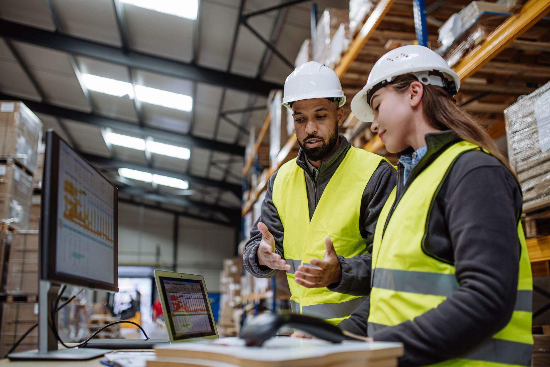 Warehouse staff reviewing logistics data at a workstation. Warehouse staff reviewing logistics data at a workstation.