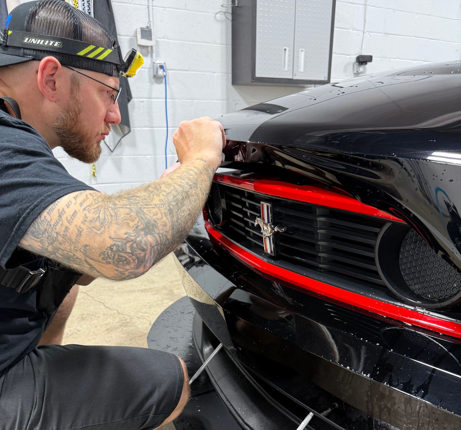 A man is applying window tinting to a car door