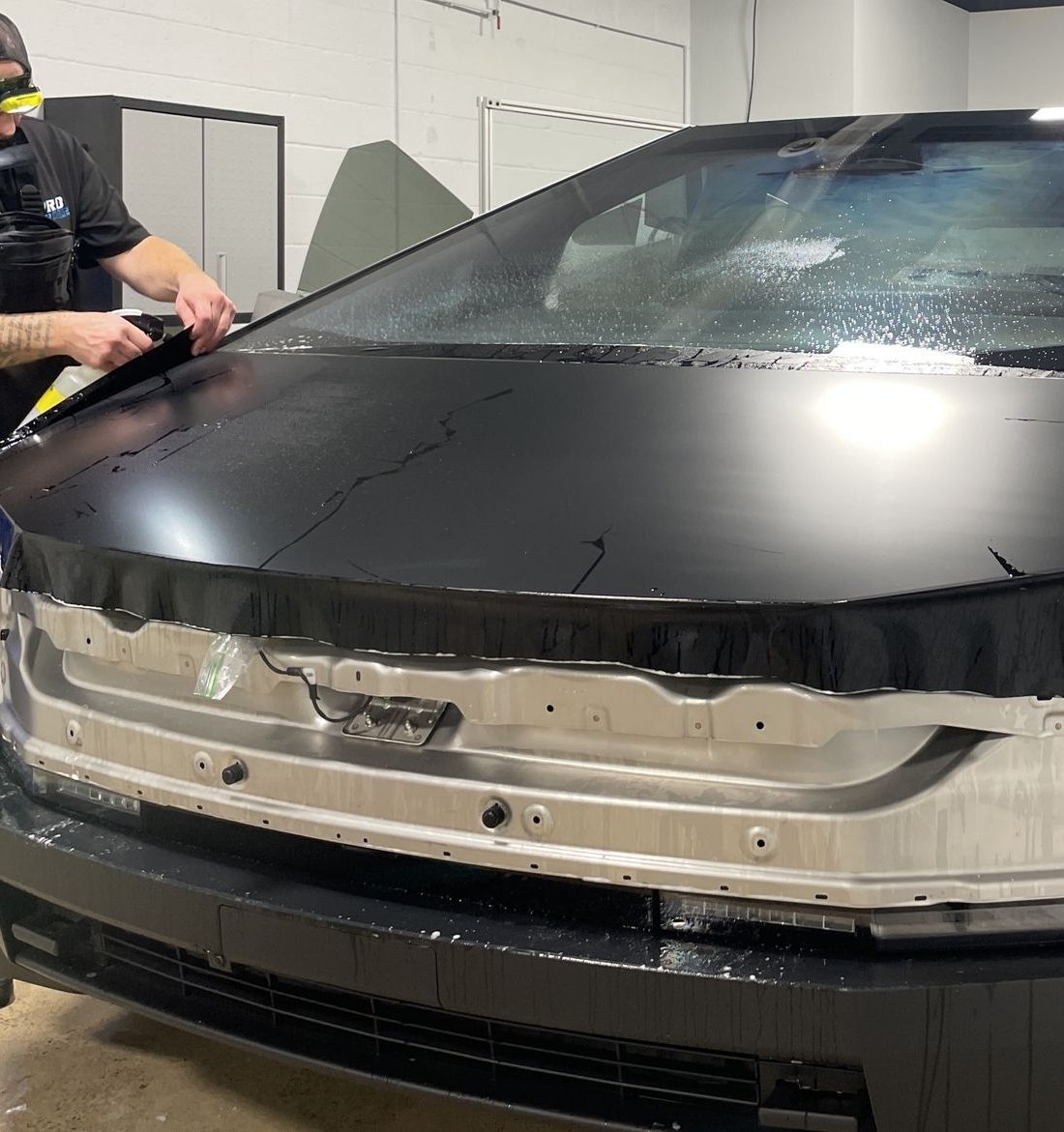 A man is cleaning the wheel of a black car with a sponge.