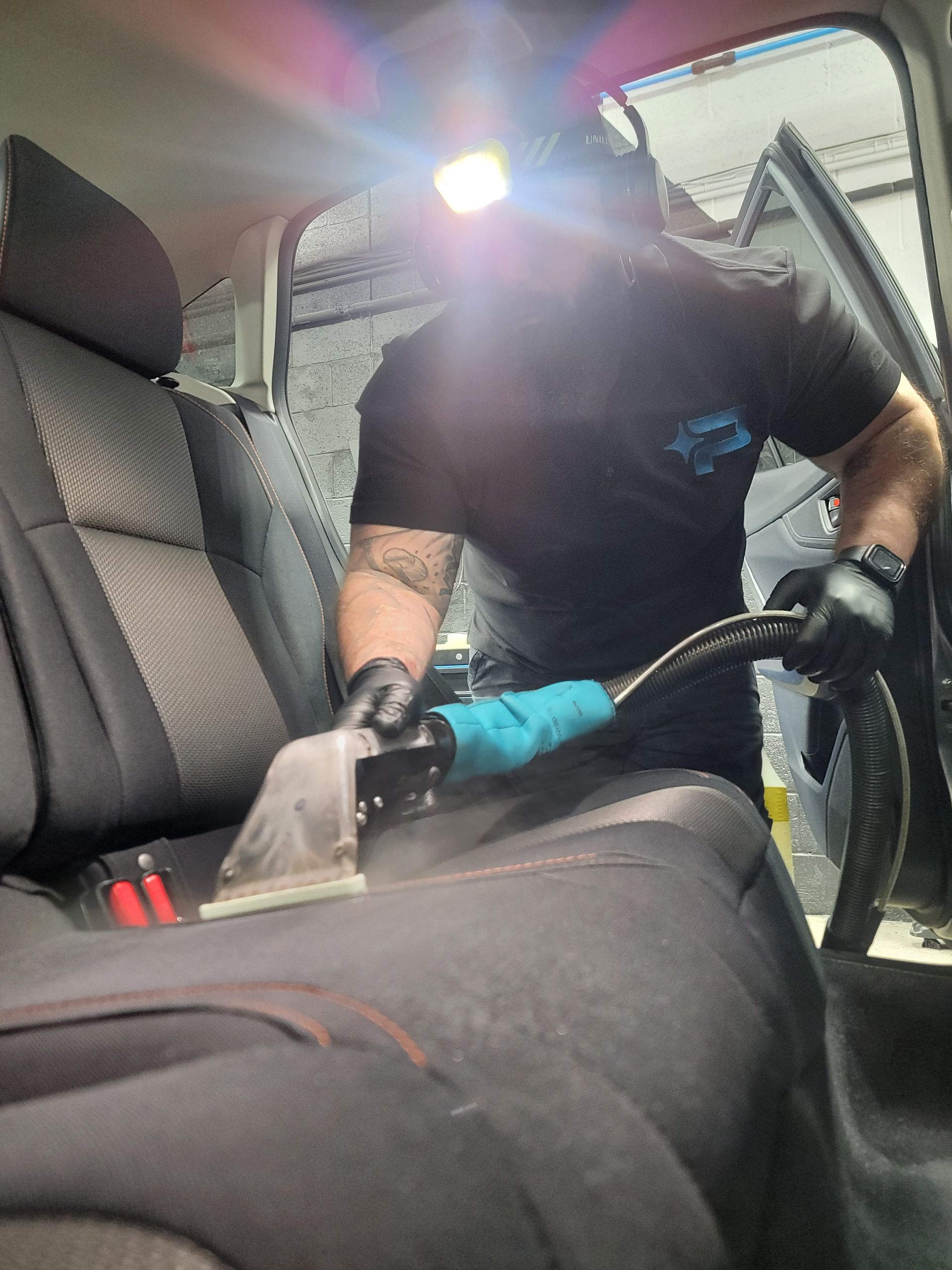 A man is cleaning the wheel of a black car with a sponge.