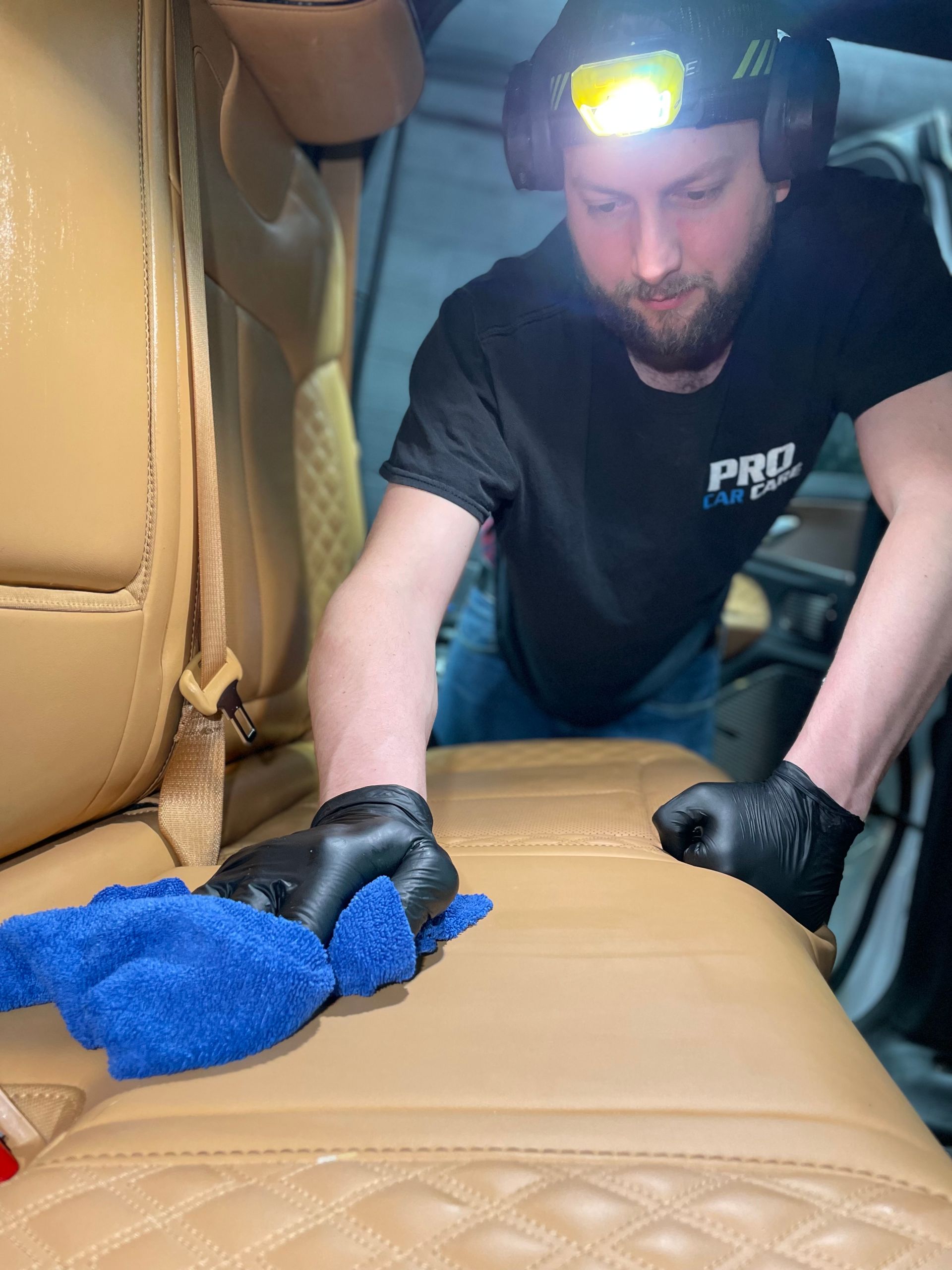 A person is applying a clear film to the hood of a car.