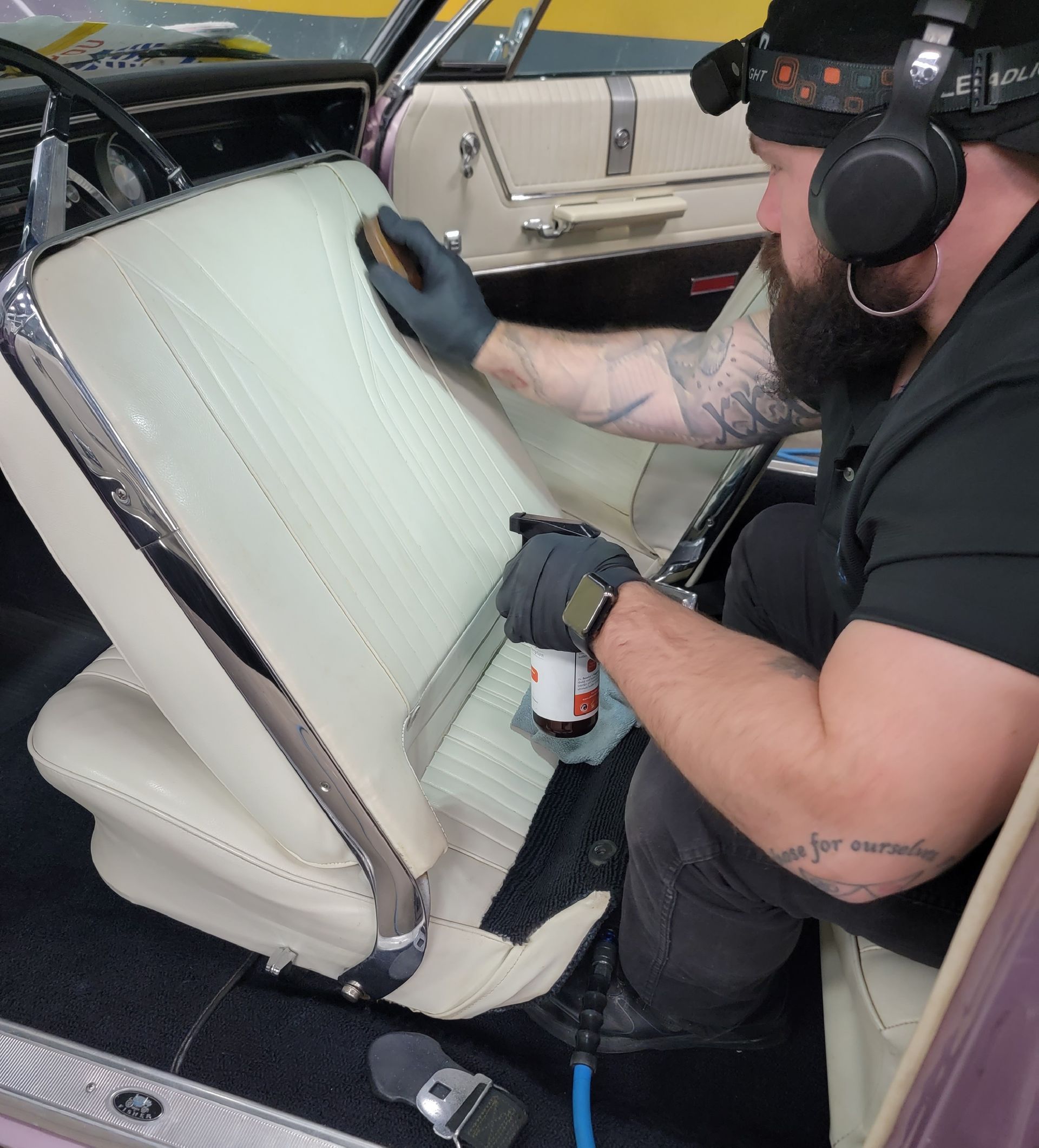 A man wearing headphones is working on the interior of a car
