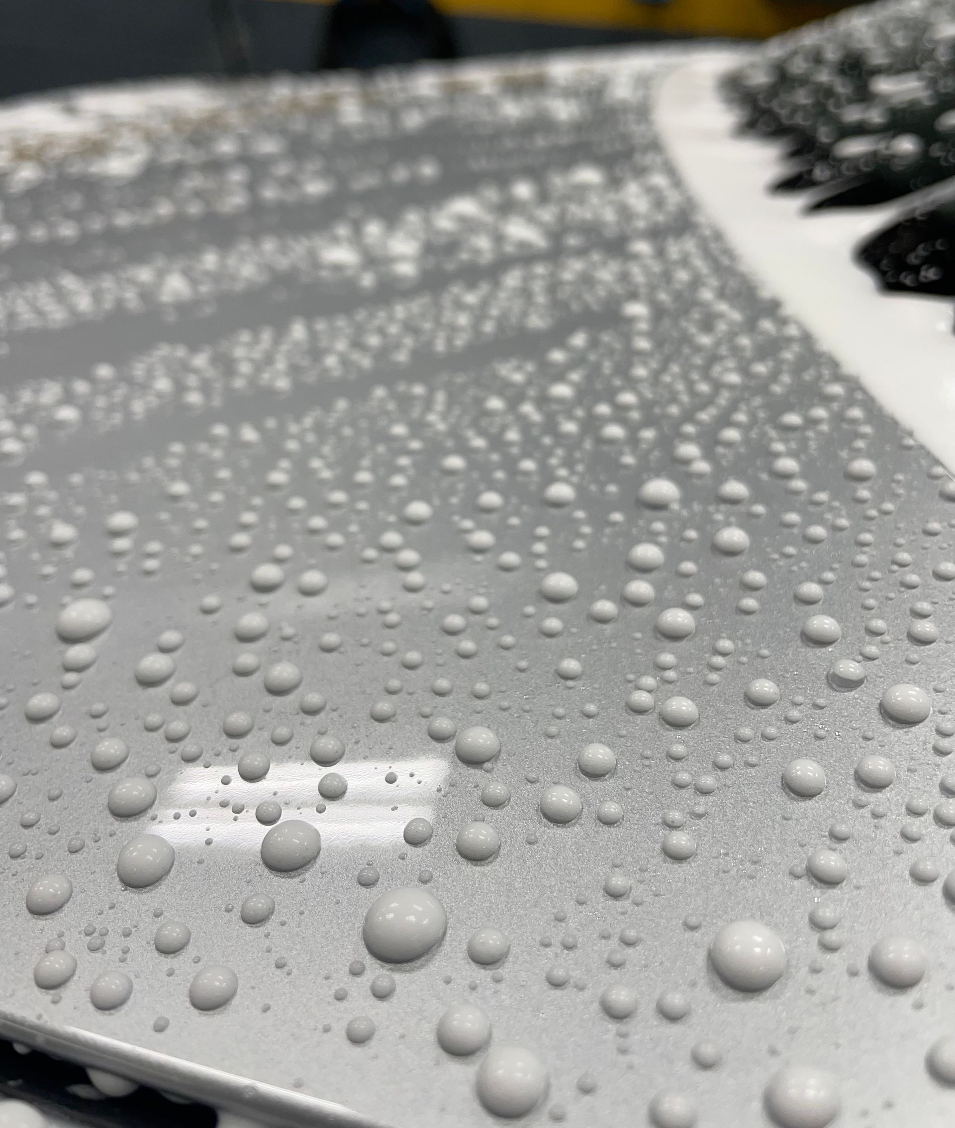 A close up of water drops on a silver surface.