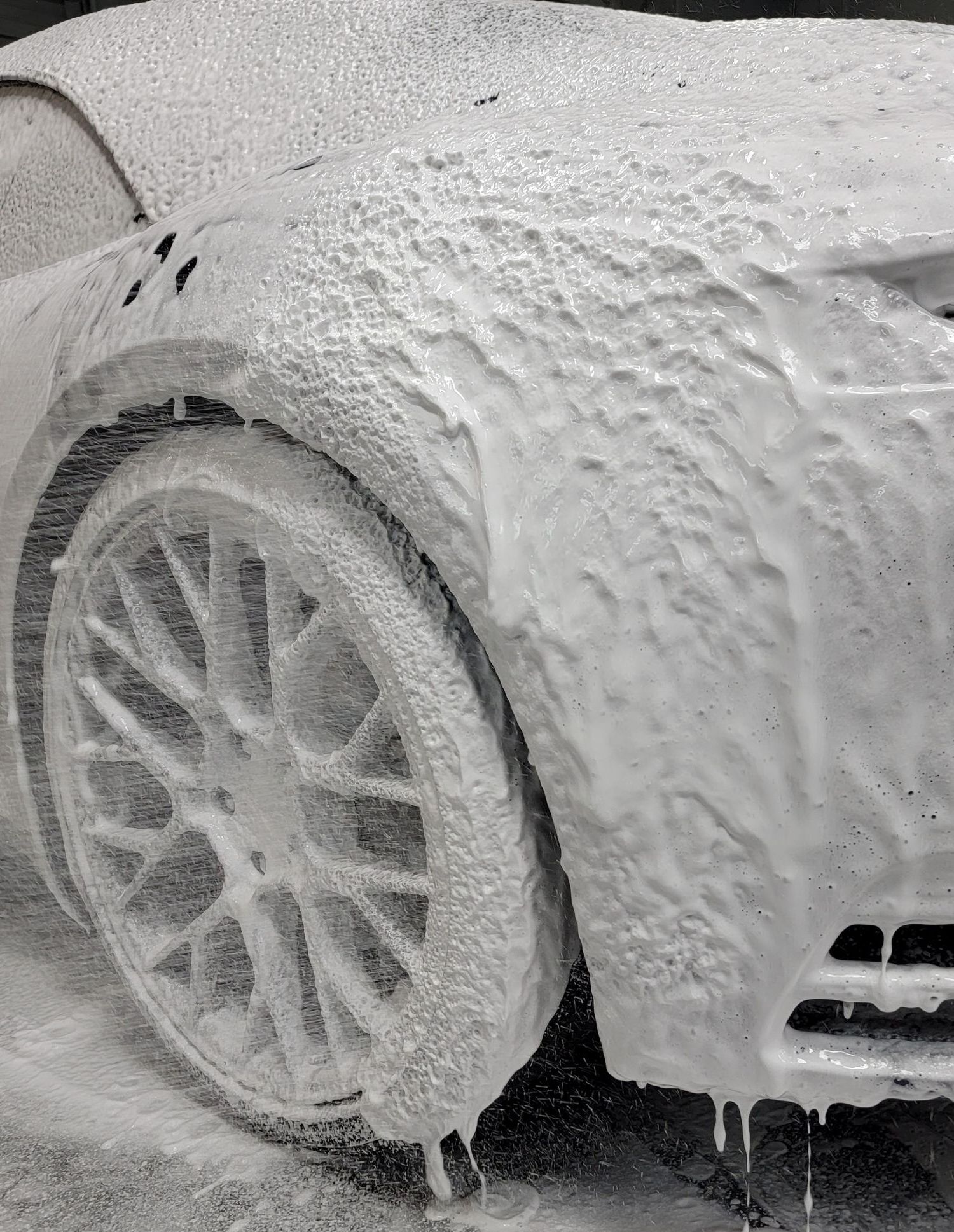 A car is covered in plastic wrap in a garage.