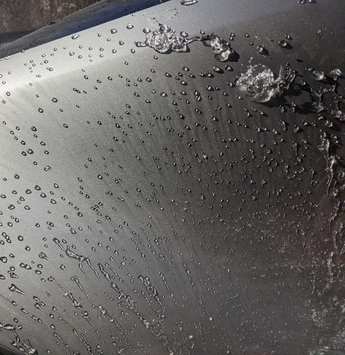 A man is cleaning the wheel of a black car with a sponge.
