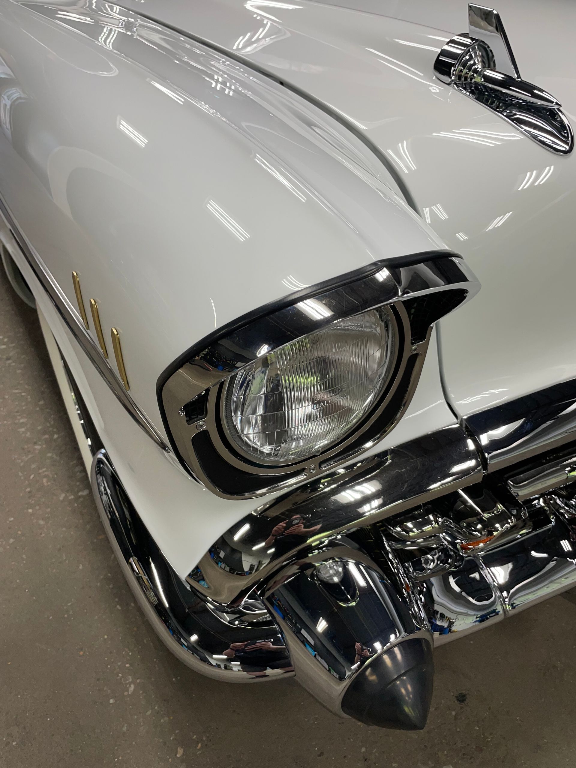 A close up of a white car with a chrome headlight