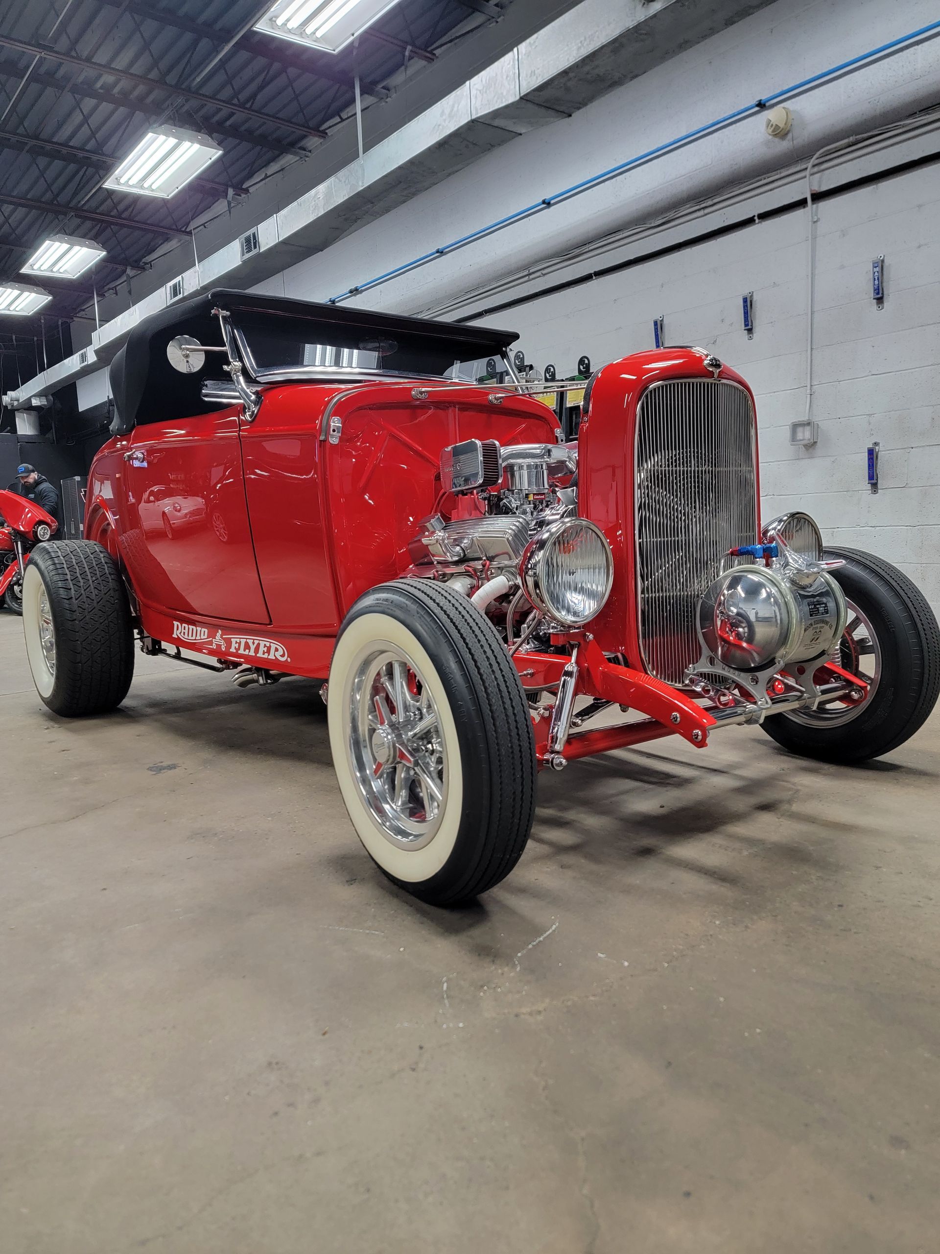 A red hot rod is parked in a garage.