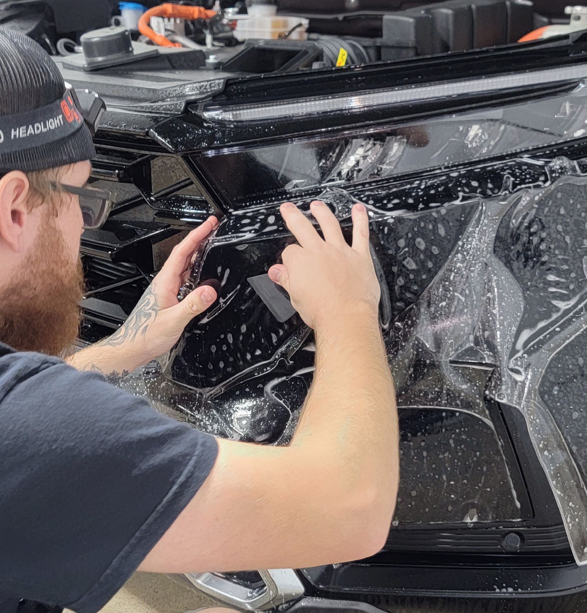 A man is wrapping a car with plastic wrap.