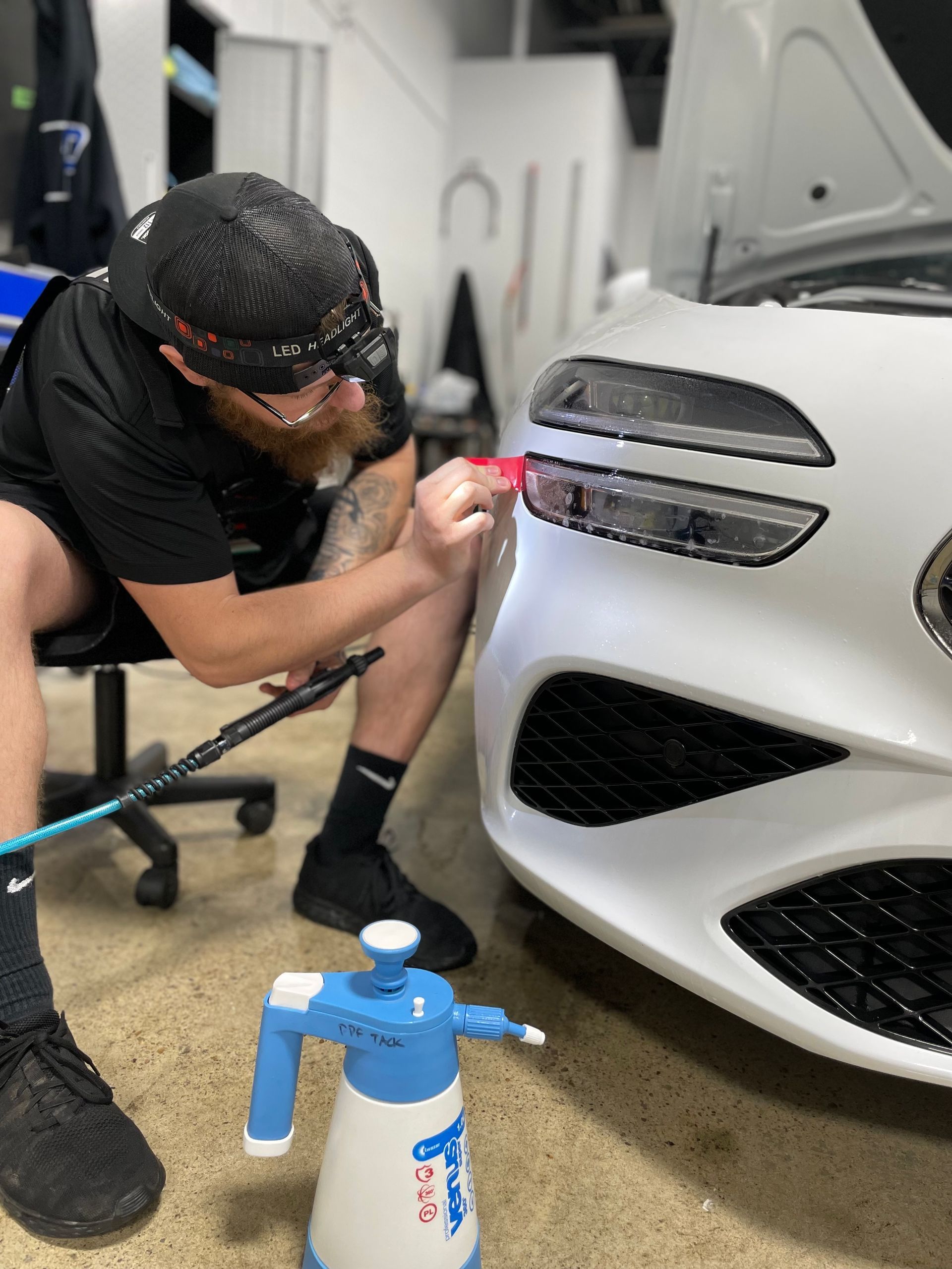 A man is cleaning the wheel of a black car with a sponge.