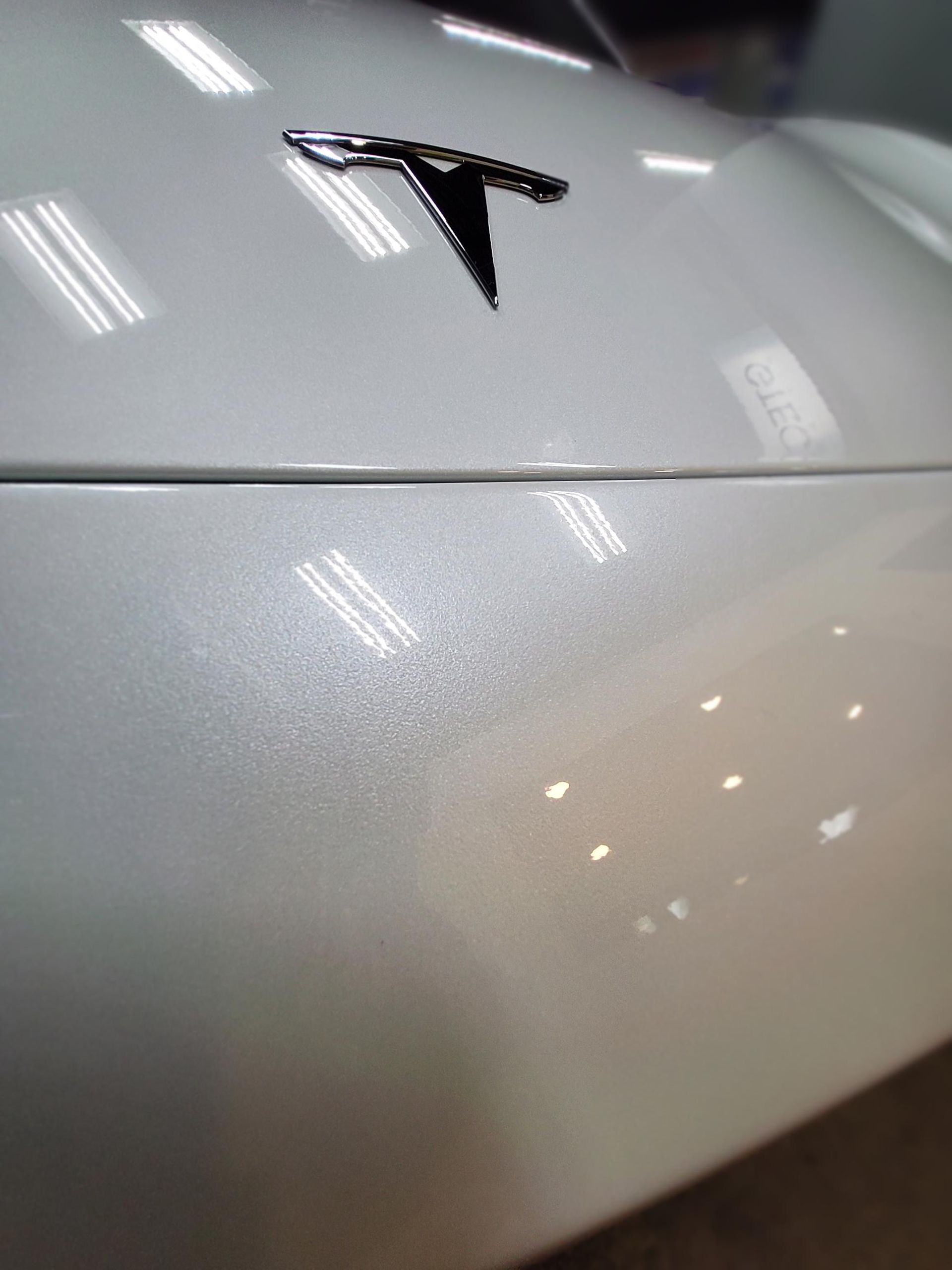 A person is applying a clear film to the hood of a car.
