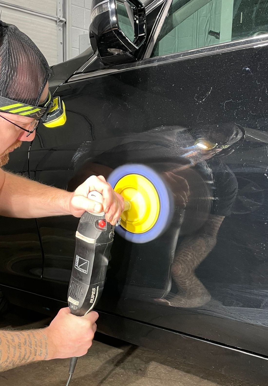 A person is applying a clear film to the hood of a car.