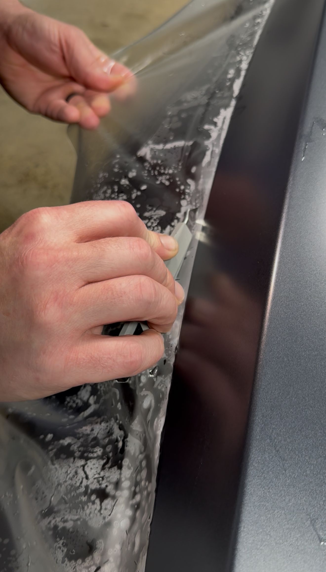 A man is cleaning the wheel of a black car with a sponge.