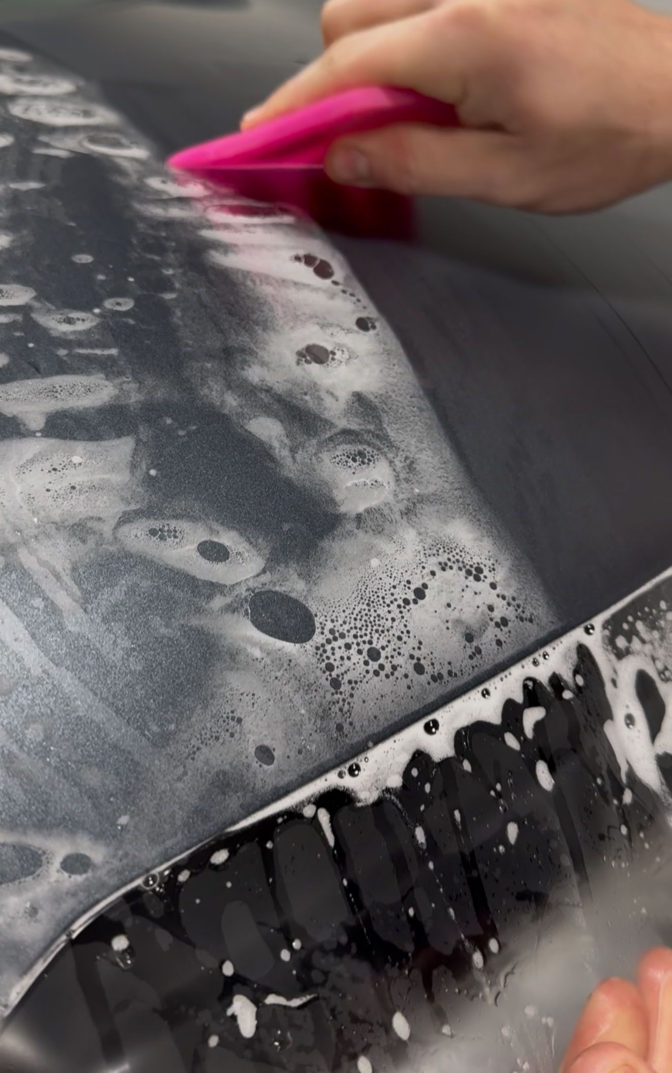 A person is washing a car wheel with foam