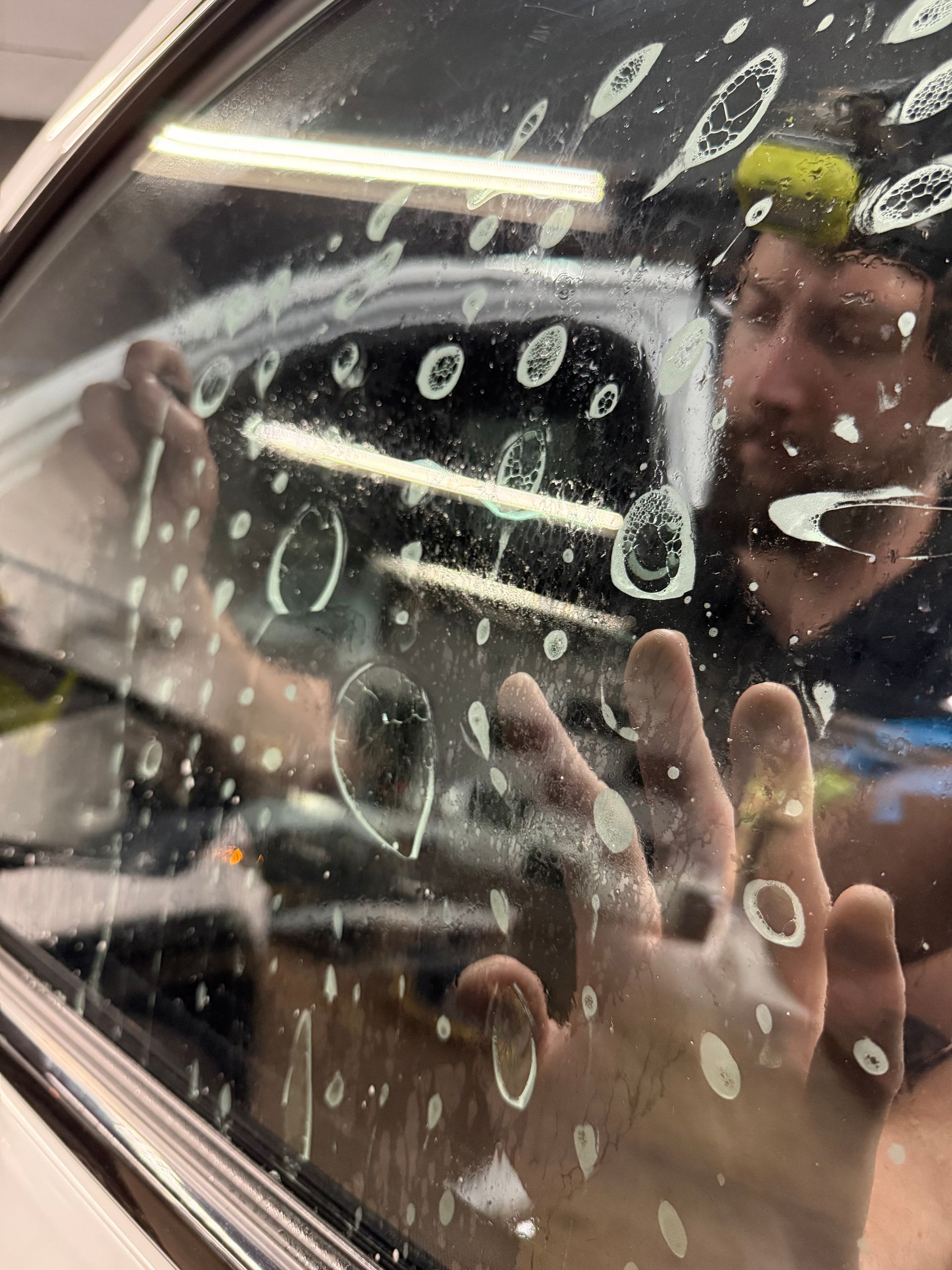 A person is applying a clear film to the hood of a car.