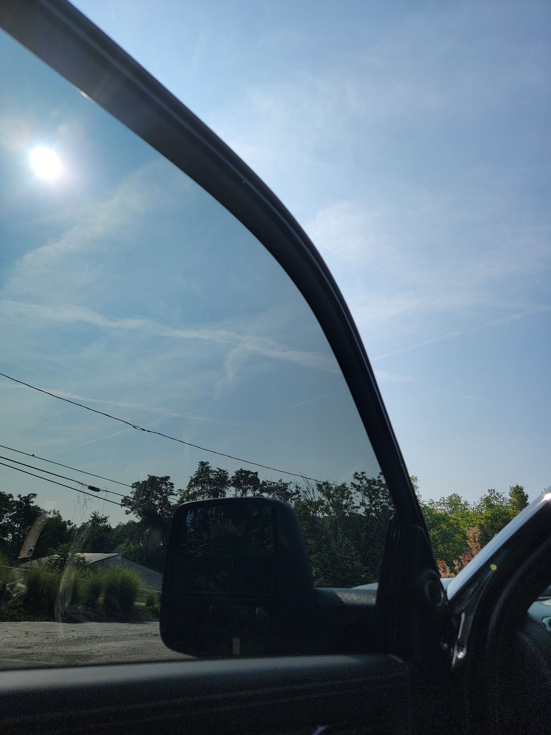 A man is applying a protective film to the hood of a red car.