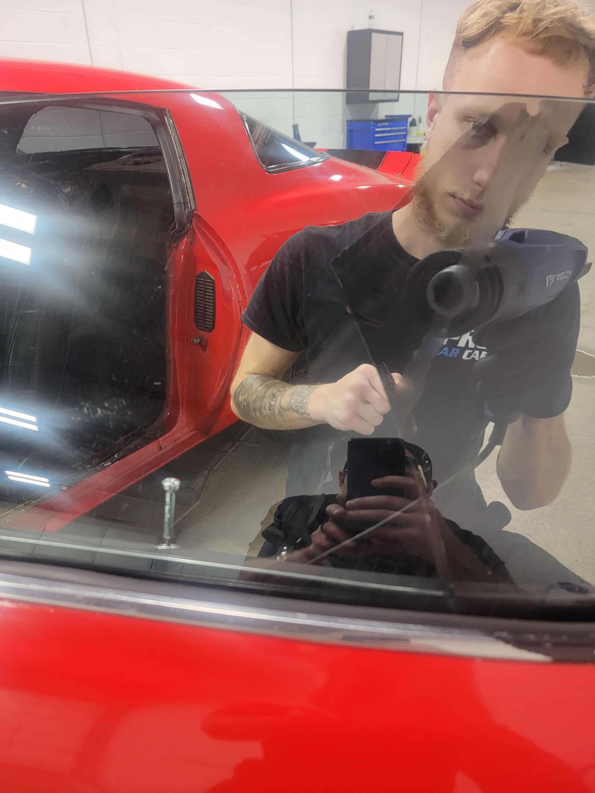 A man is cleaning the wheel of a black car with a sponge.