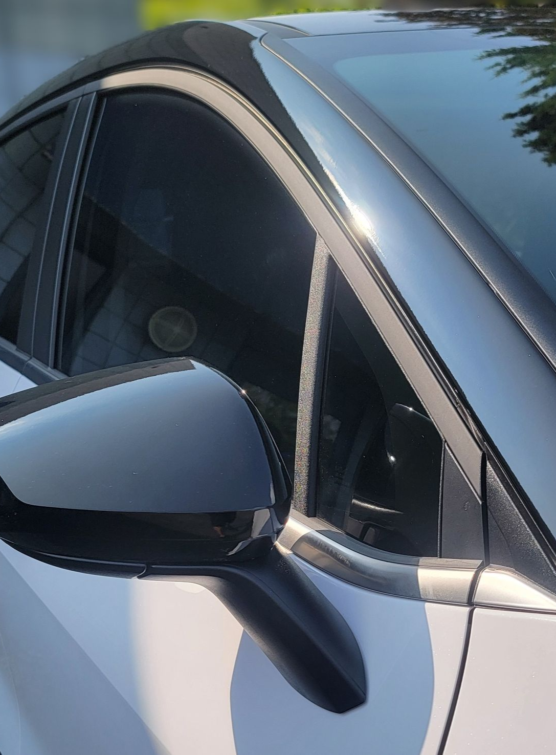 A man is cleaning the wheel of a black car with a sponge.