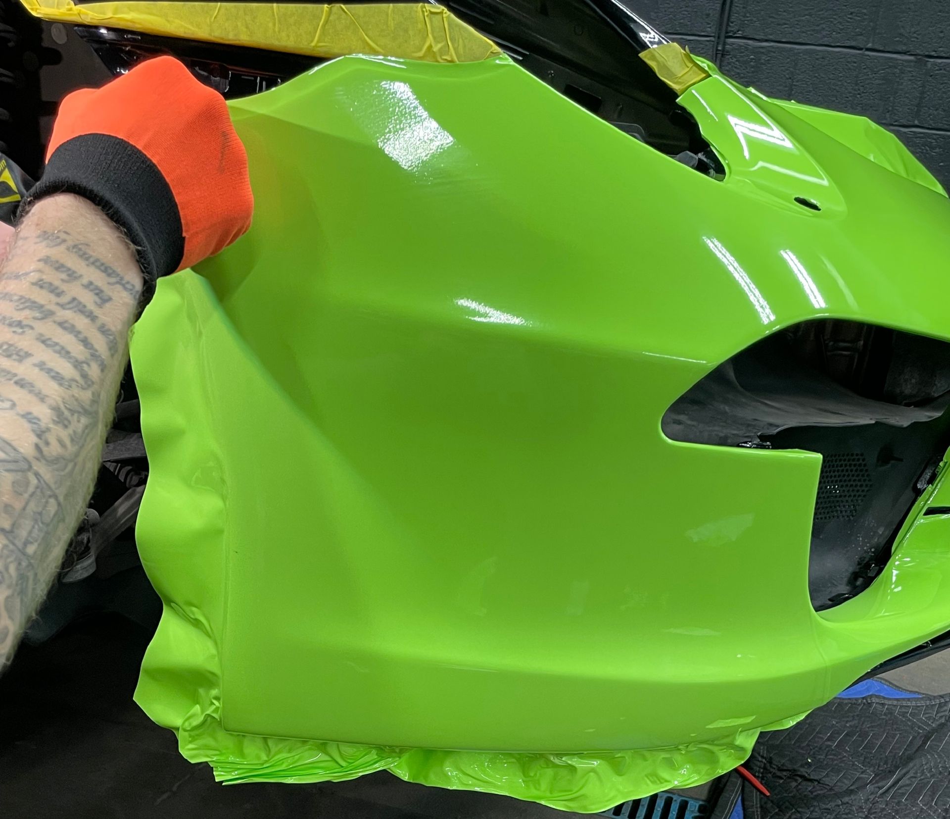 A man is cleaning the wheel of a black car with a sponge.